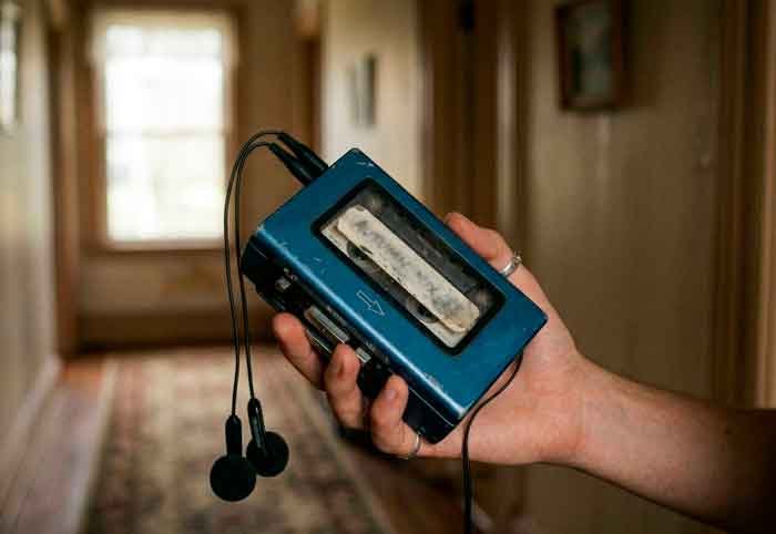Walkman azul con auriculares en un pasillo iluminado suavemente, en una escena poética y melancólica.