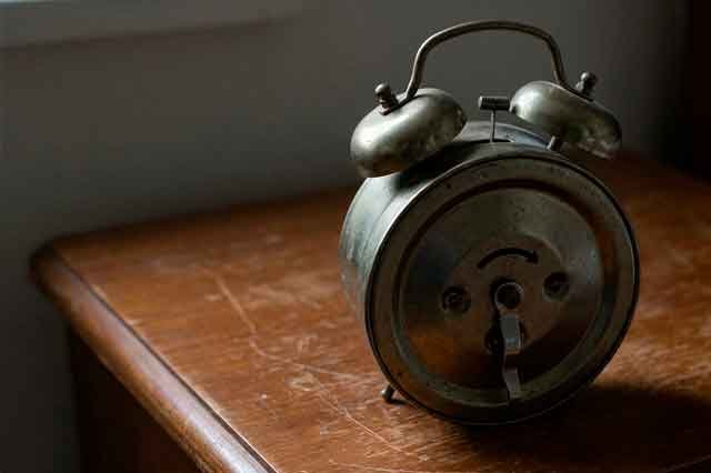 Despertador metálico antiguo en una habitación en penumbra